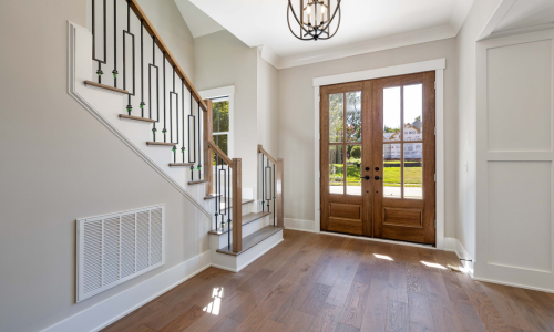 An interior front door next to a staircase with white decorative millwork.