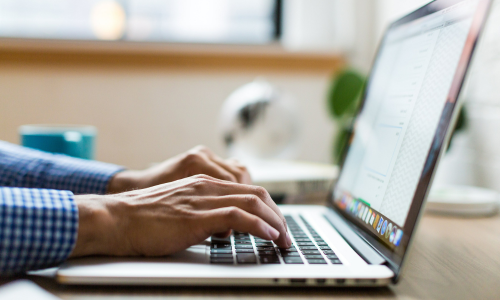 A close-up of hands typing on a laptop.